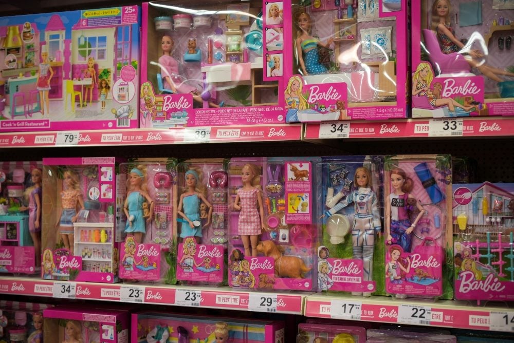 Rows of Barbie dolls in their packages on a store shelf with the Barbie brand name visible on the packaging in piece about cult brands and DAMs.