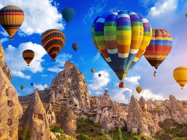Brightly colored hot air balloons rise over the dramatic landscape of over Cappadocia, Turkey, suggesting the importance of customer insights. 