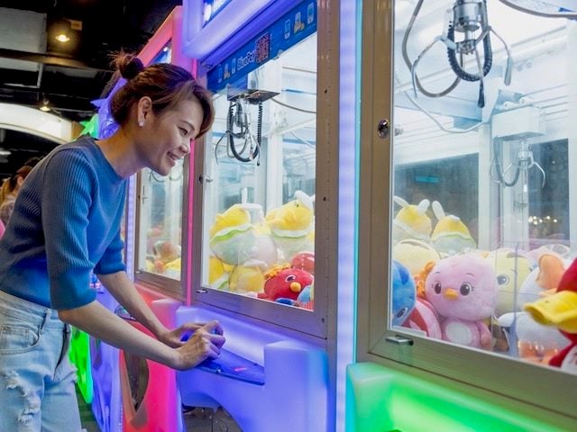 woman playing claw game in arcade