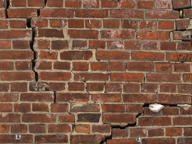 A cracked brick wall - cracks in infrastructure concept