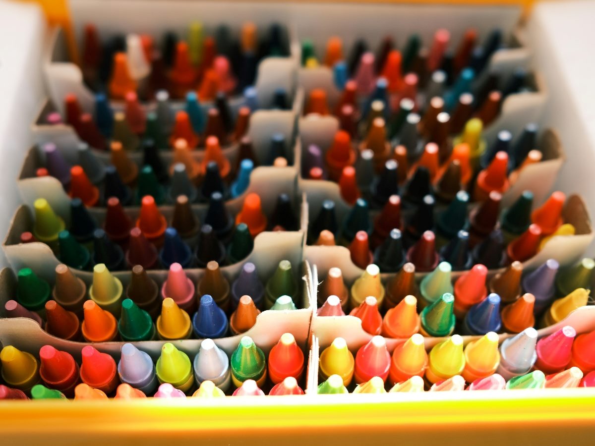 Dozens of colored crayons in a box.