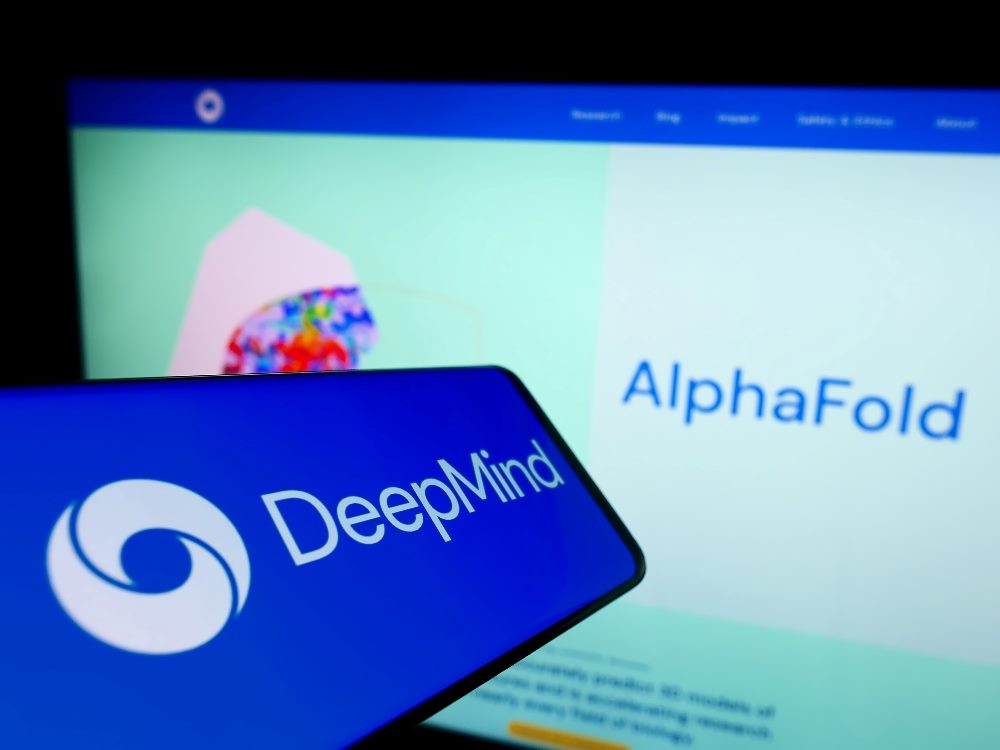 Mobile phone with logo of AI company DeepMind Technologies Limited on screen in front of the AlphaFold web page in piece about Google DeepMind's Demis Hassabis.