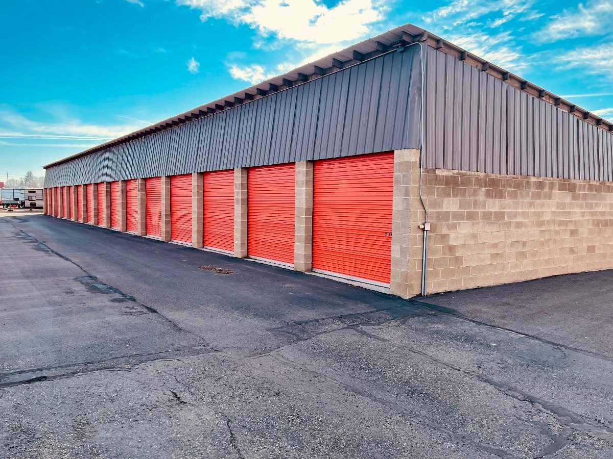 A building containing storage rooms, with an orange-colored door for each of the approximate 10 rooms showed.