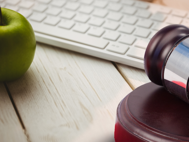 Gavel, keyboard and an apple on wooden table top