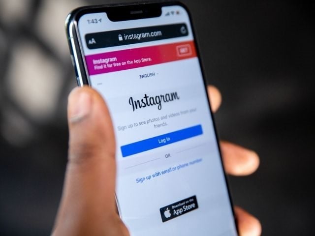 Hand holding mobile phone with Instagram app open. 