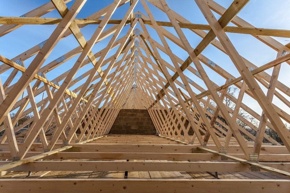 A wooden house truss framework against a blue sky in a piece about LLM agents.