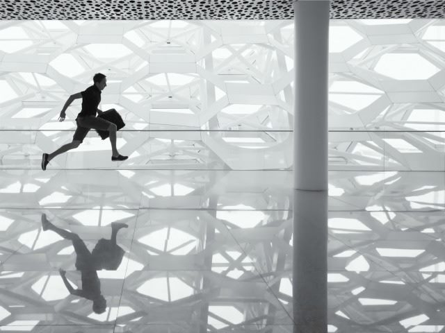 person running through an empty hall with briefcase in hand
