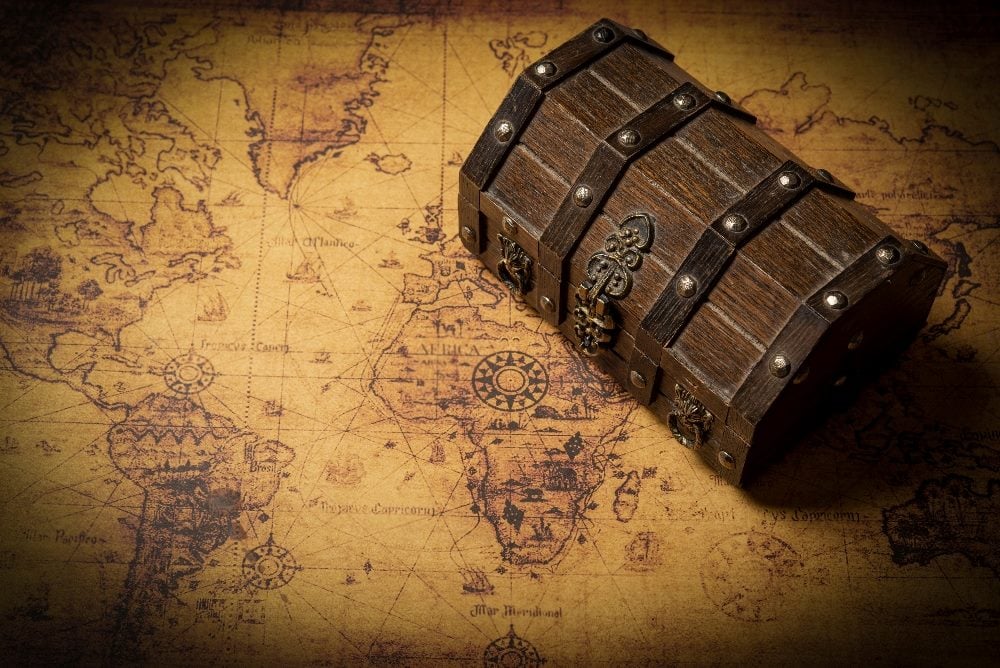 A classic treasure chest sits on top of a vintage world map in piece about the retail shopping experience.