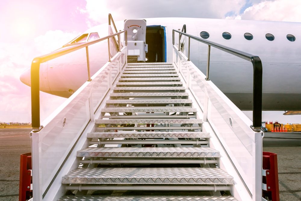 A plane sits on the tarmac in the sun with stairs leading up to the door for passenger onboarding suggesting the importance of customer onboarding in product led business strategies.