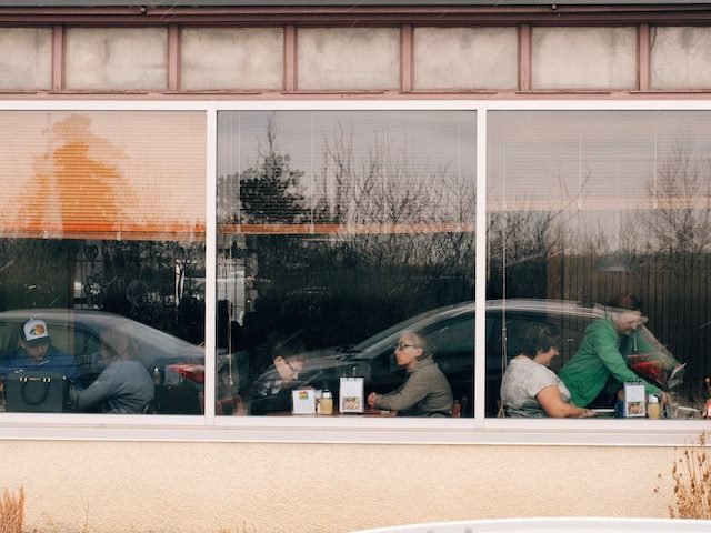 exterior shot of a diner, with patrons and waiter visible