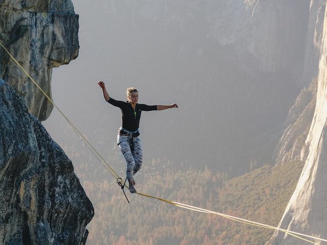 woman walking a tightrope between two mountains