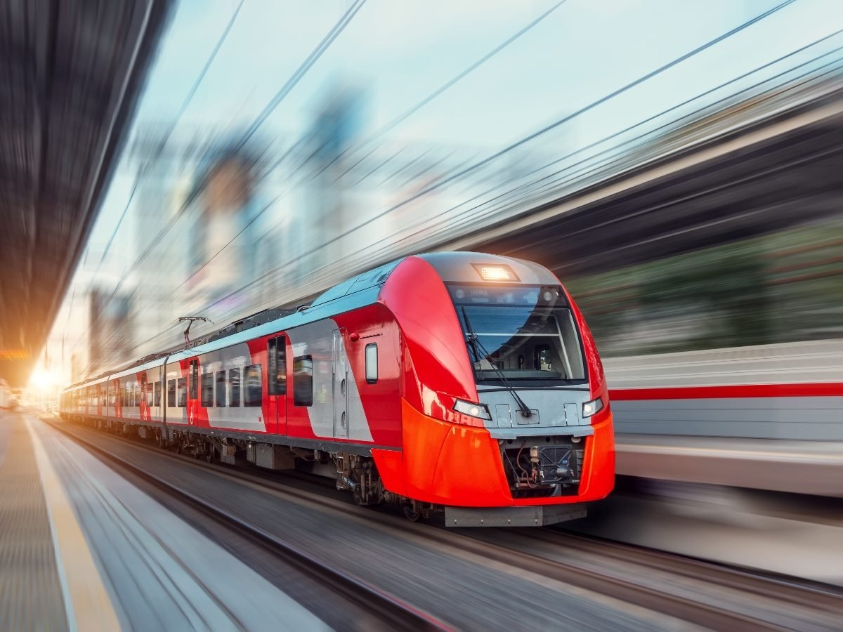 A modern red high-speed train races through a station, symbolizing acceleration and forward momentum.