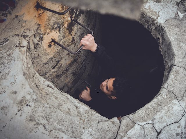 man climbing up out of a tunnel