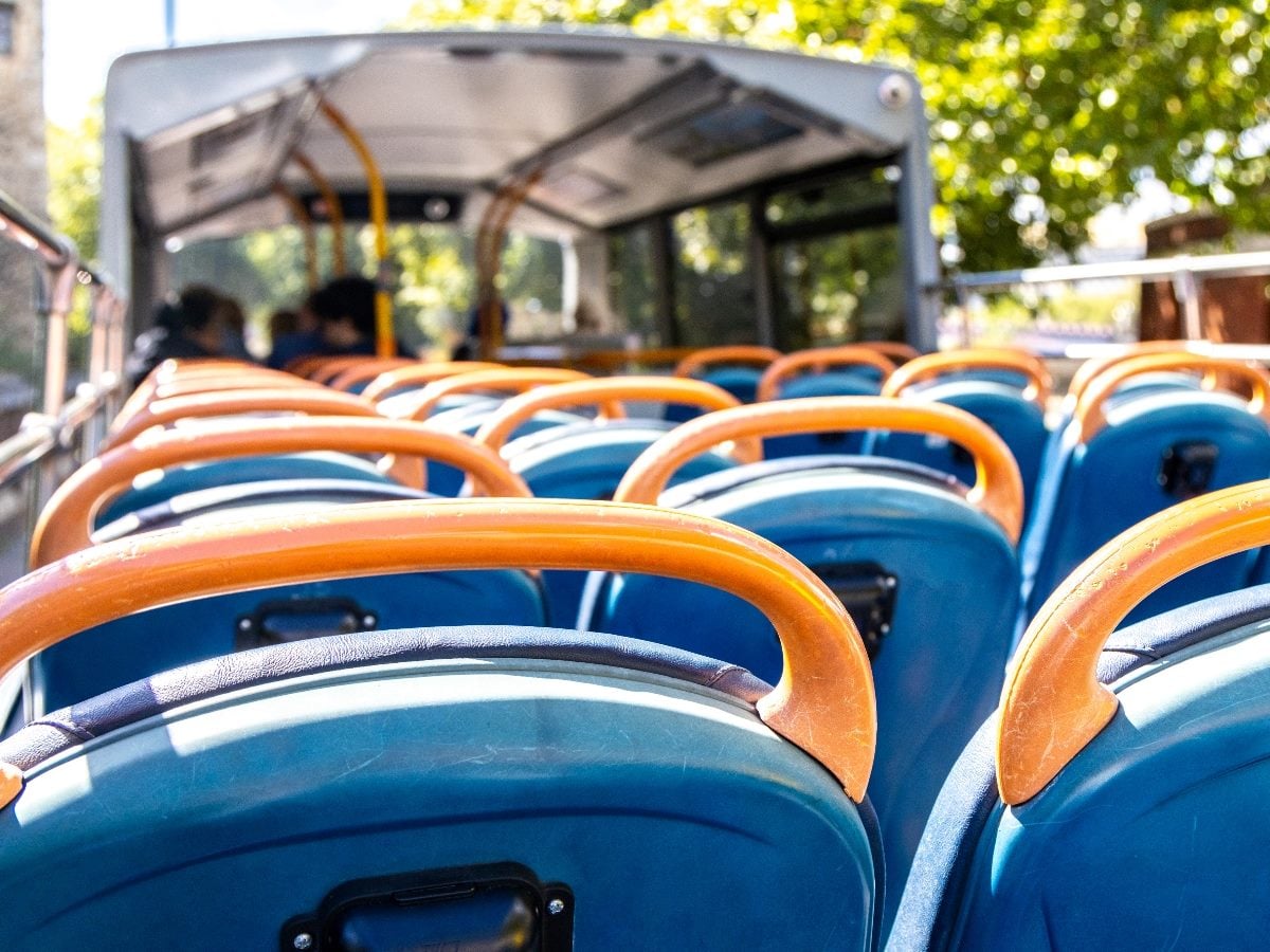 Rows of empty blue seats with orange handrails on an open-top city bus, viewed from the passenger perspective, symbolizing structured journeys and shared digital pathways.