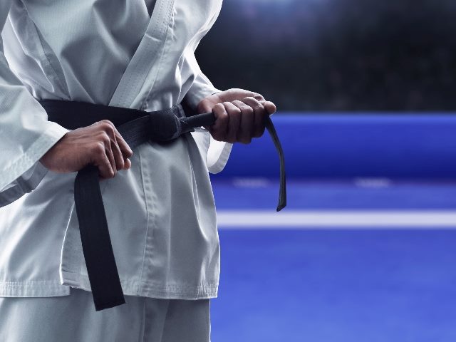  Karate martial arts fighter putting on belt getting ready to compete.