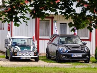  Mini Clubman and classic Austin Mini Cooper retro vehicle parked against the background of a house at the International Mini Meeting 2012 in Hungary.