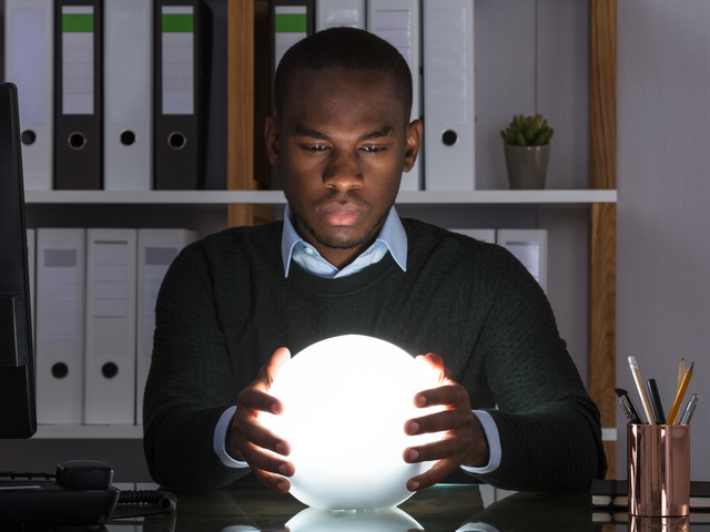 A businessman using a crystal ball to predict the future of his business' ecommerce outlook