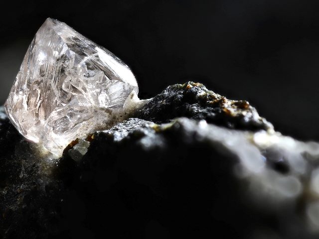 A natural diamond nestled in dark kimberlite igneous rock in a mine in a piece about product knowledge and the buyer's journey.