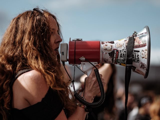 woman with a bullhorn speaking at a protest in London