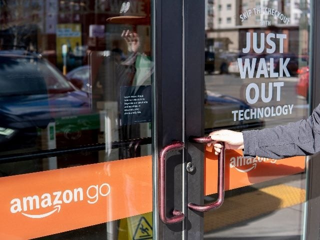 Man opens glass door of the Amazon Go store with slogan "Just Walk Out."