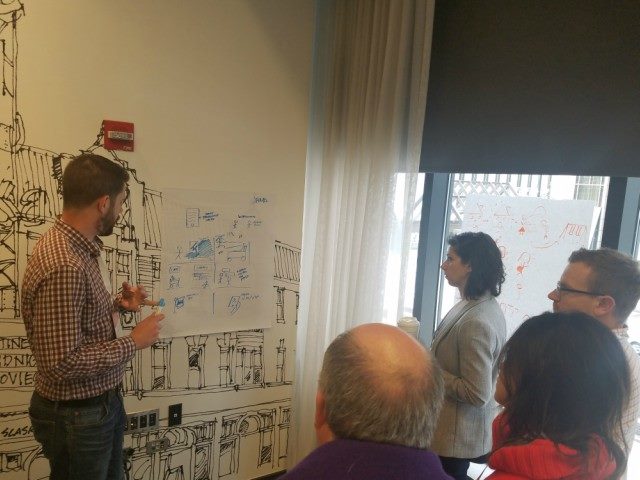 People gathered around scrap paper taped to a wall.