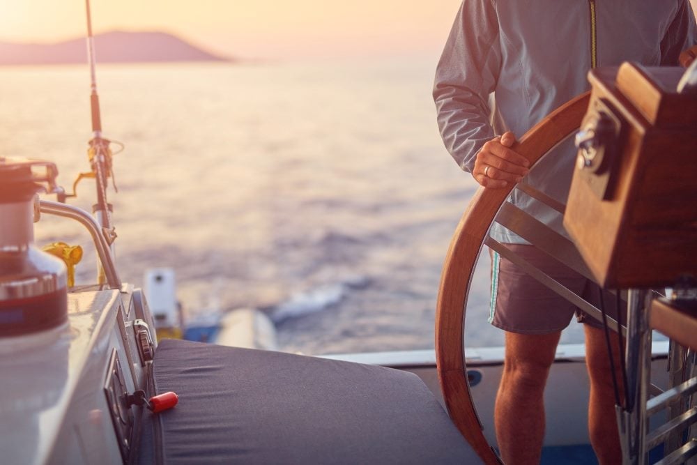 A captain of a ship guides it through the waters as he stands at the ship's wheel with an island and water and sky in the background in piece about data strategists.