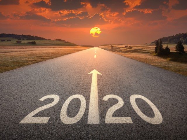 An illustration of 2020 written on the road of an empty highway at sunset.