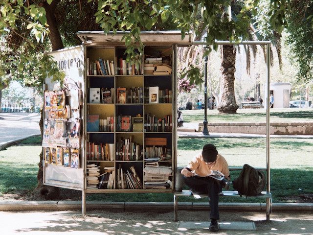 man reading on an outside bench