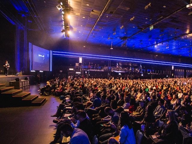 in person  conference with a crowded audience watching a speaker on the stage
