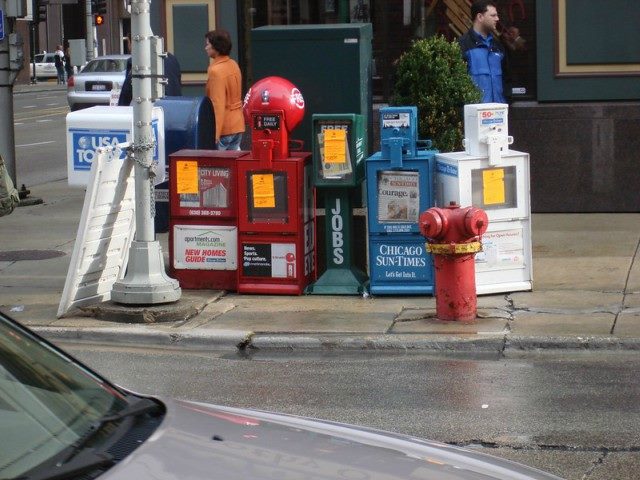 Newspaper stands on a street corner.