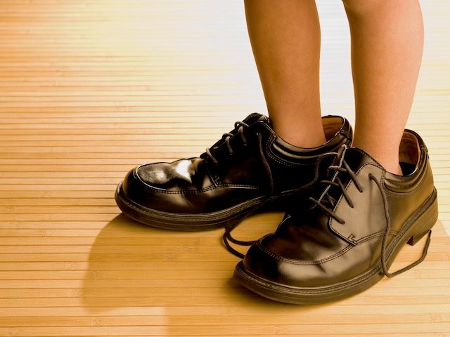 kid trying on shoes  that are  too big for them