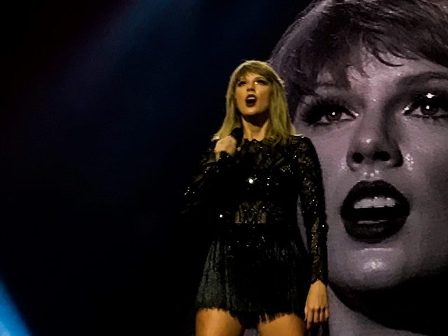 Taylor Swift performe on stage with a video image of her face behind her in piece about branding strategies and brand authenticity. 