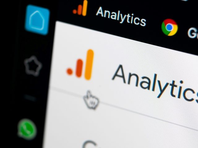 Google Analytics homepage on Apple iMac screen close-up and the Google Analytics icon in red and orange and Google logo in red, yellow, green and blue. 