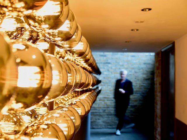 person rounding the corner into a  well-lit hallway covered in gold-tinted lights
