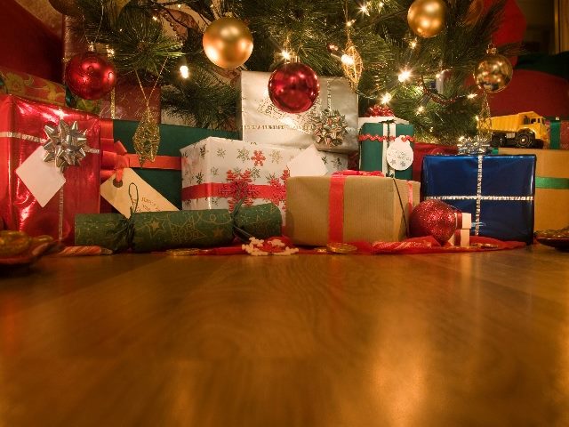 A warm and beautiful shot of wrapped Christmas gifts under a tree with two candles burning nearby in piece about emotional marketing. 