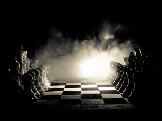 Chess figures on a dark background with smoke and fog - strategy concept