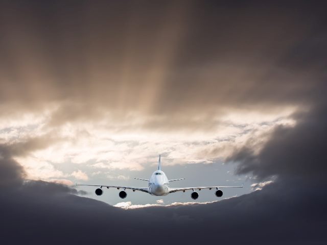 Commercial airplane flying under a storm amid clouds. 