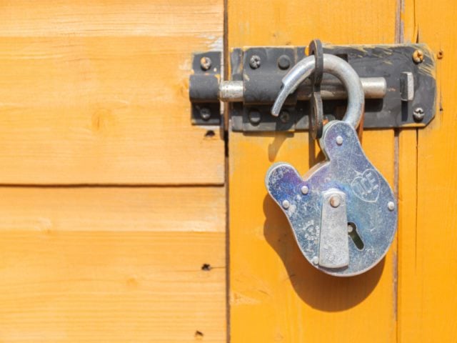 open padlock on an orange colored door