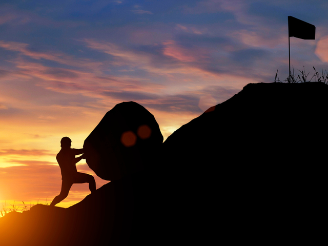A marketing manager trying and failing to roll a giant boulder up a hill to the flag/goal - customer expectations concept