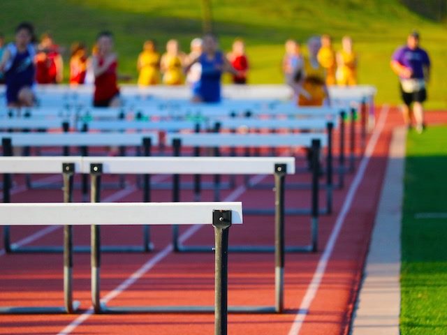 blurry out of focus runners leaping over hurdles on a track