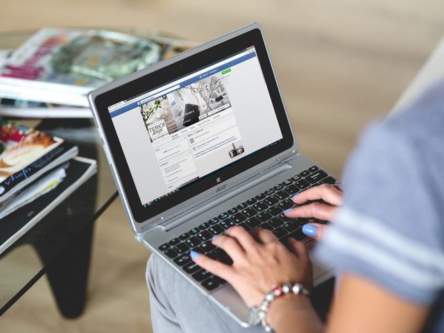 woman using facebook with her hands on a laptop