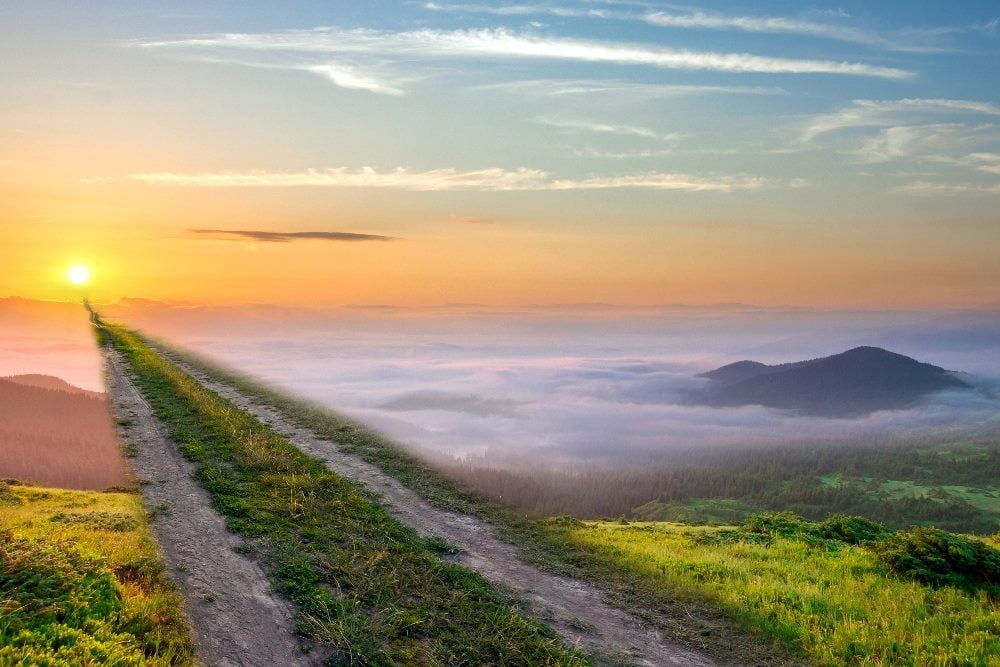 Gravel dirt road between wheat fields stretching to distant mountains on horizon in piece about the future of AI-powered marketing.