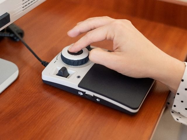  A woman -- showing just her hand -- uses a special magnification device for the visually impaired. 