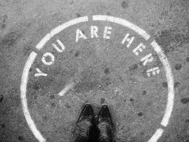 shoes in a circle on pavement with writing stating "you are here"