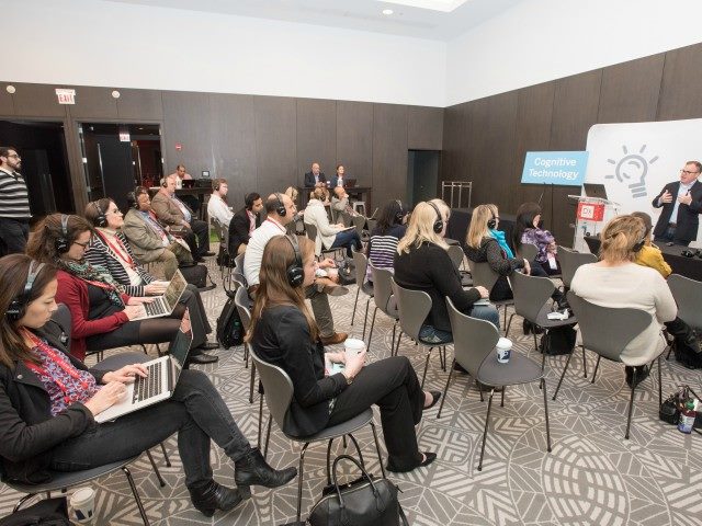 Photo of CMSWire DX Summit attendees with headshots on listening to a speaker in the innovation garden.