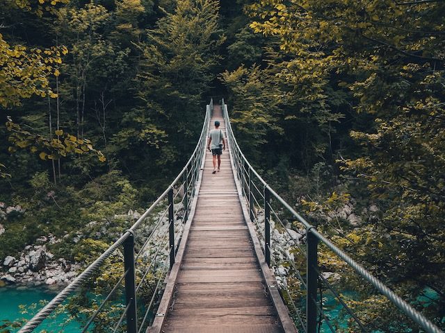 person crossing a bridge over a river