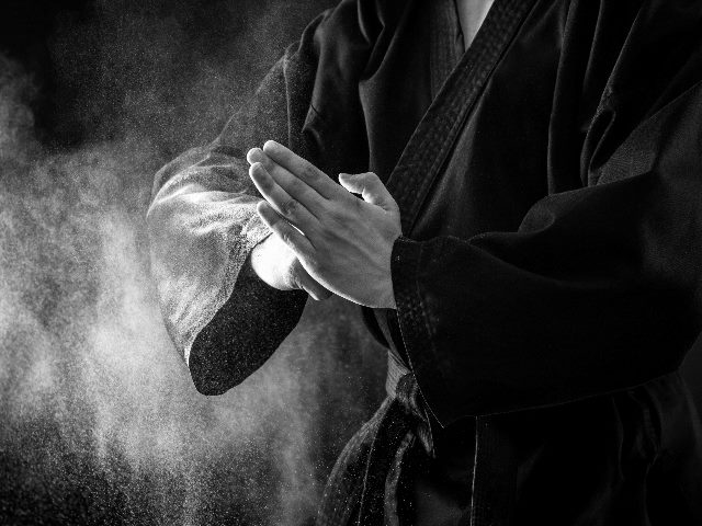 Closeup of male karate fighter hands in a master karate pose in a black and white photo.