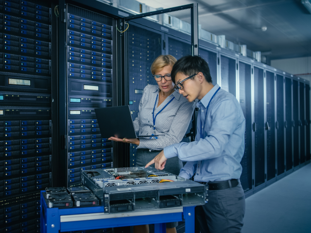 Two IT pros working on a server that powers cloud computing