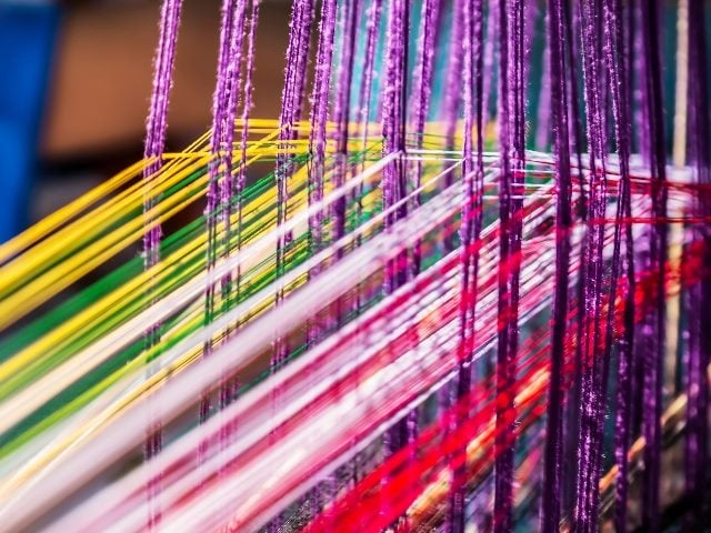 A manual loom hand weave threaded with brightly colored thread in piece about omnichannel customer service.
