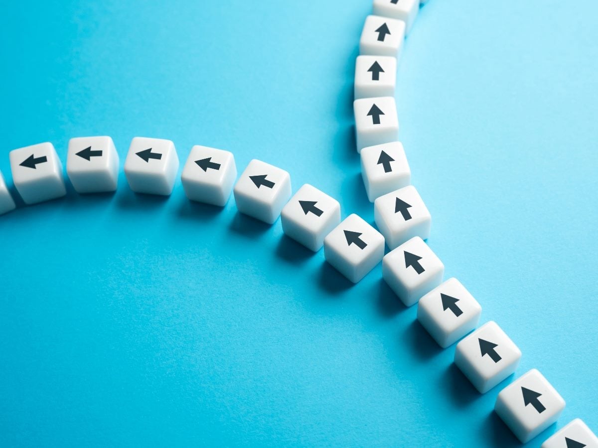 White cube blocks with black arrows arranged in a line that splits into two directions on a blue background.